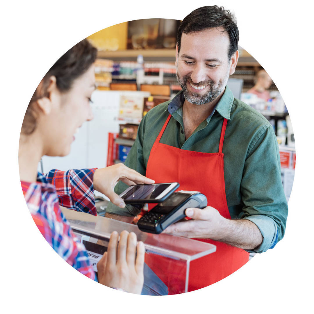 Woman using her phone to pay for her groceries. Employee holding the contactless reader up to her phone.