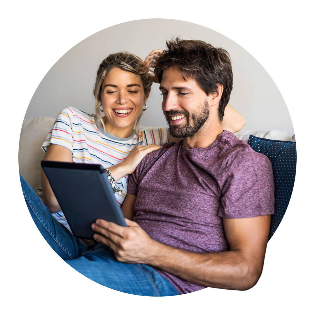 Smiling young couple using digital tablet at home.