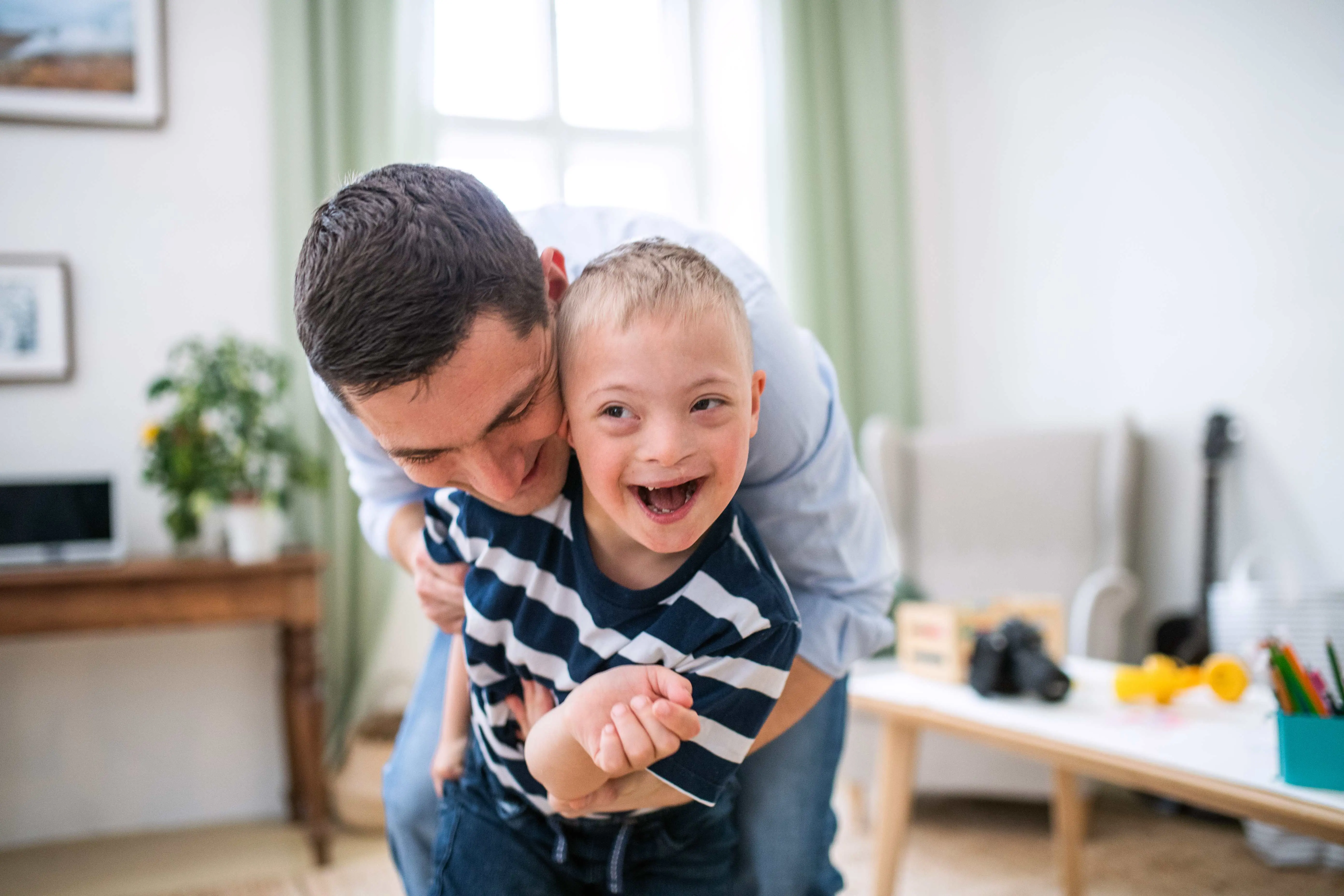Father laughing and hugging a child with special needs